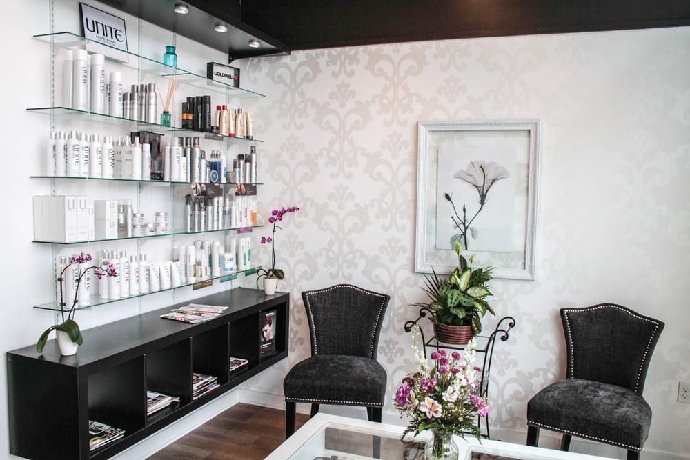 The waiting area: two upholstered chairs beside fresh flowers, facing a wall of product shelves.
