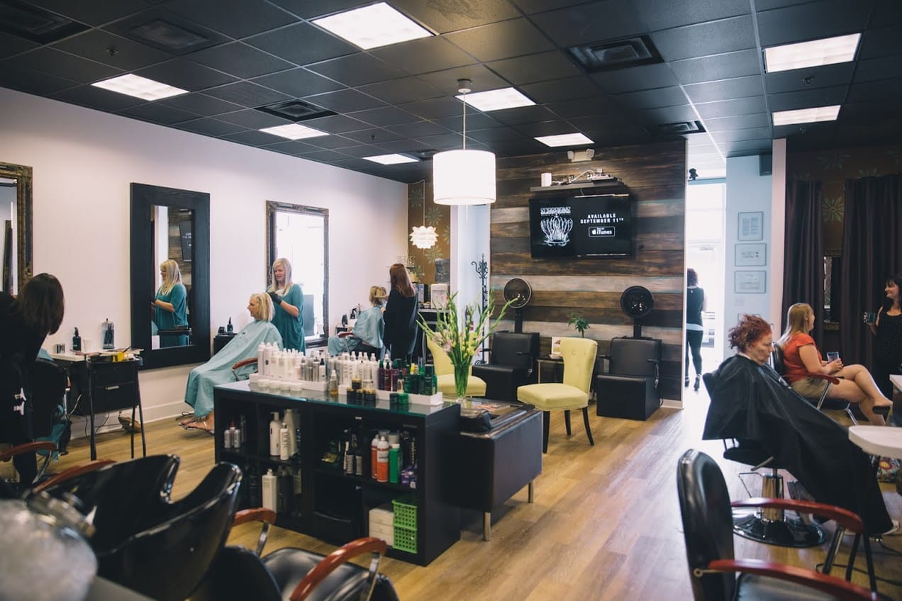 The styling floor mid-appointment, with stylists working at the mirrors and clients waiting along the far wall.